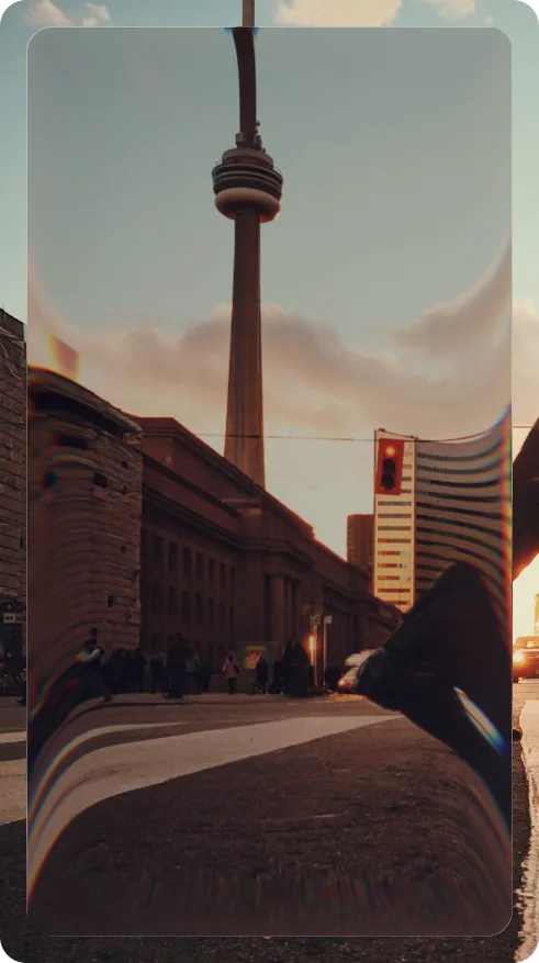 A pedestrian stepping across a downtown Toronto street at sunset, the CN Tower behind