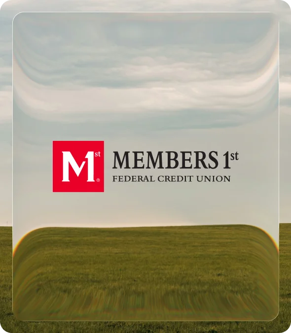 The Members 1st Federal Credit Union logo on a glass panel over a photograph of a grass field under an overcast sky
